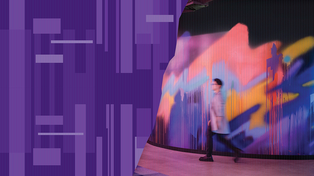 A person standing in front of a wall with a colorful design.